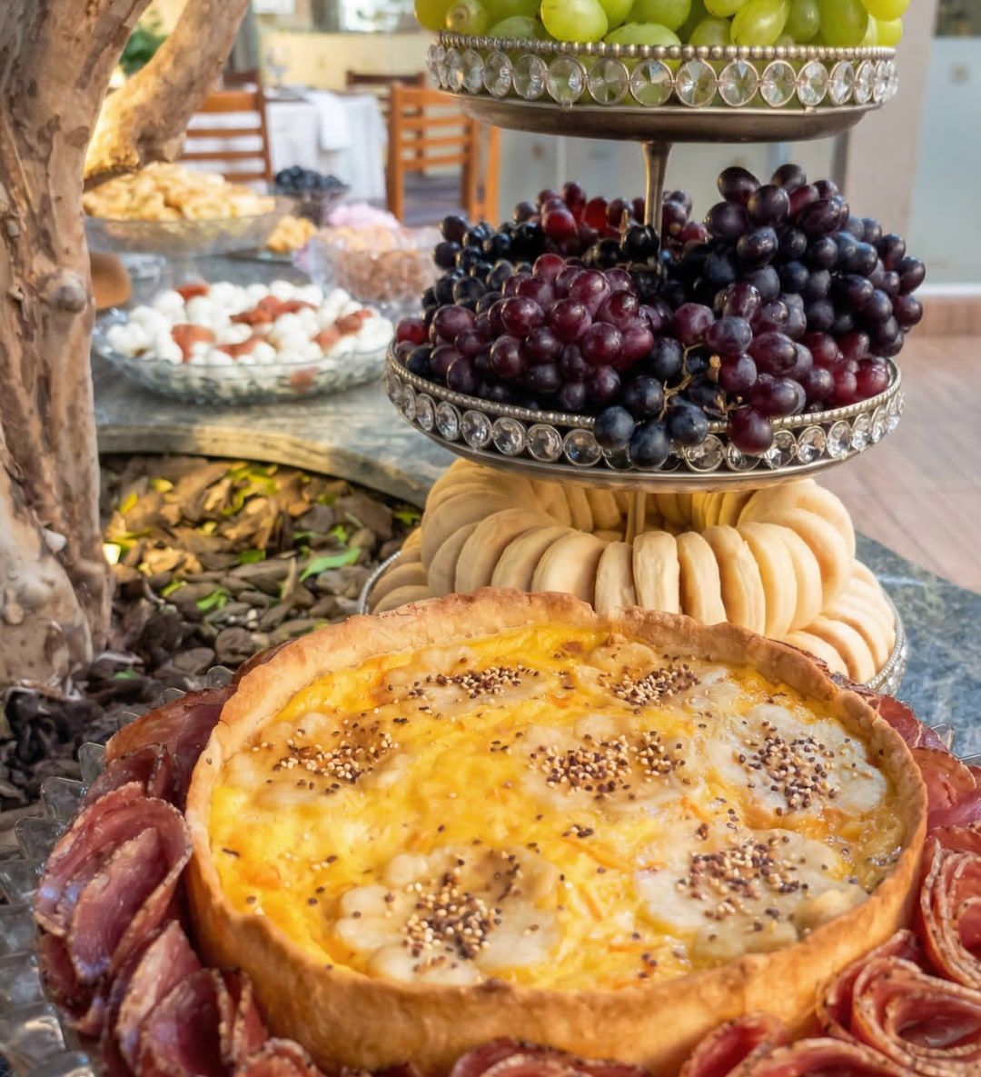 Quiche dourada com frios e uvas em mesa de buffet